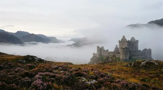 Atmospheric Scottish castle ruins shrouded in morning mist during autumn off-peak season