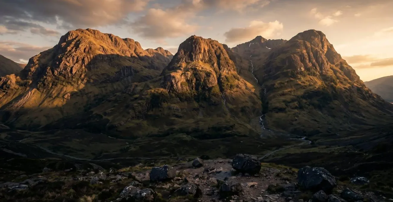 The Three Sisters volcanic peaks in Glencoe illuminated by golden hour light showing glacial carving
